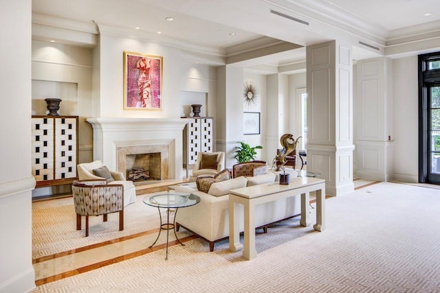 living room featuring crown molding, a high end fireplace, and decorative columns