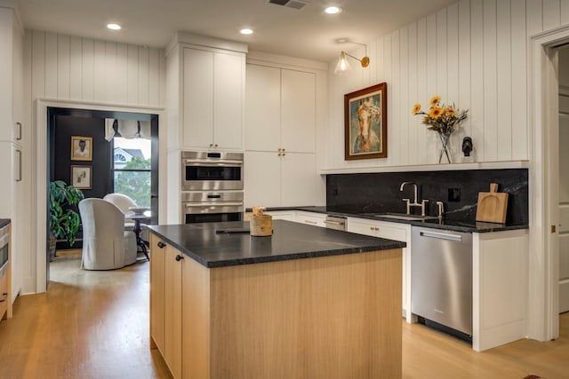 kitchen featuring sink, white cabinetry, light hardwood / wood-style flooring, a kitchen island, and stainless steel appliances