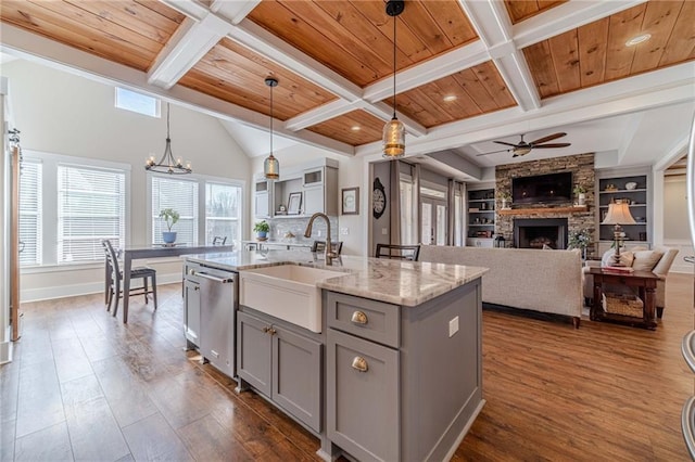 kitchen with pendant lighting, wood ceiling, built in features, dishwasher, and a center island with sink