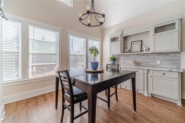 dining area with lofted ceiling, hardwood / wood-style flooring, and an inviting chandelier