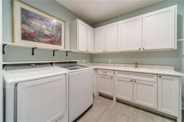 laundry area with light hardwood / wood-style floors, cabinets, washer and clothes dryer, and sink