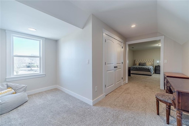 hall featuring lofted ceiling and light carpet