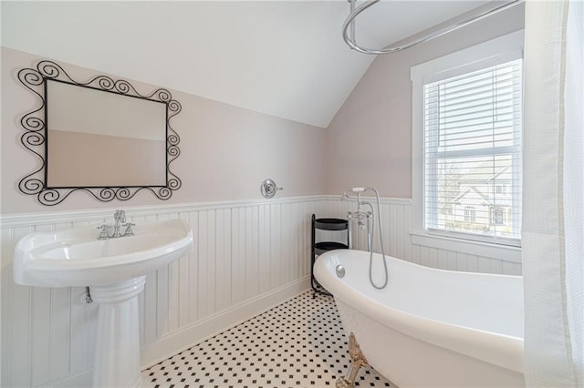 bathroom featuring a bath, lofted ceiling, and a wealth of natural light