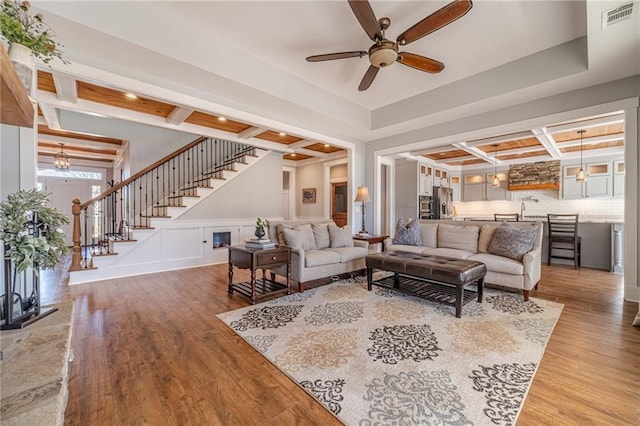 living room featuring coffered ceiling, beam ceiling, wood-type flooring, and ceiling fan