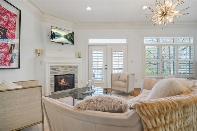 living area featuring a fireplace, a healthy amount of sunlight, crown molding, and a notable chandelier