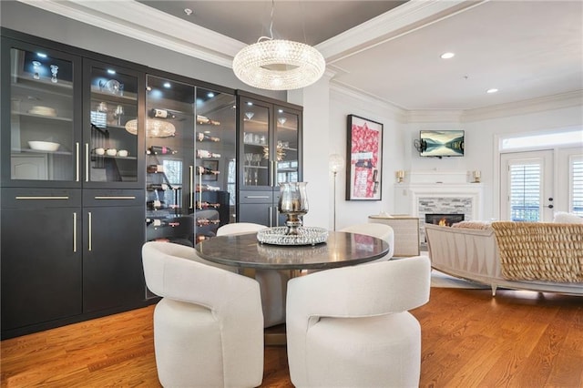 dining room featuring recessed lighting, ornamental molding, wood finished floors, and a fireplace
