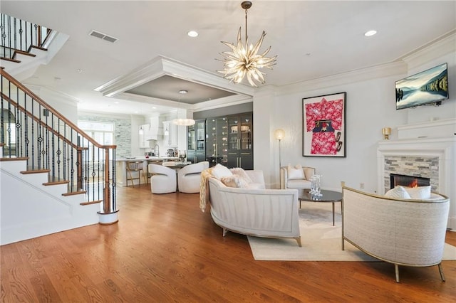 living room with visible vents, an inviting chandelier, stairway, and crown molding