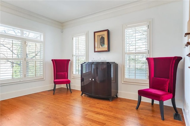 living area with light wood-style flooring, baseboards, and crown molding