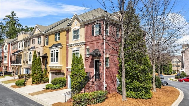 view of front of property featuring a garage, brick siding, a residential view, and concrete driveway