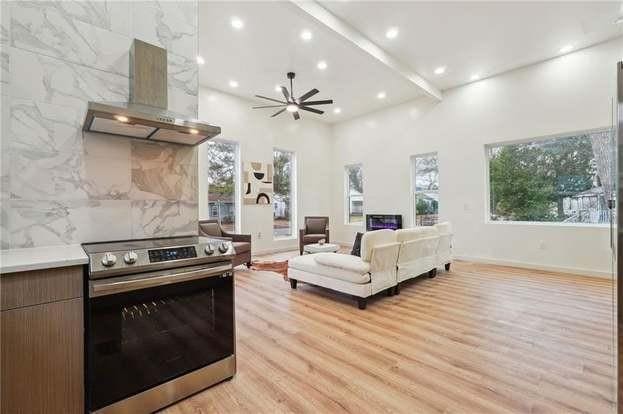 kitchen featuring ceiling fan, stainless steel range with electric stovetop, tile walls, light hardwood / wood-style floors, and island exhaust hood