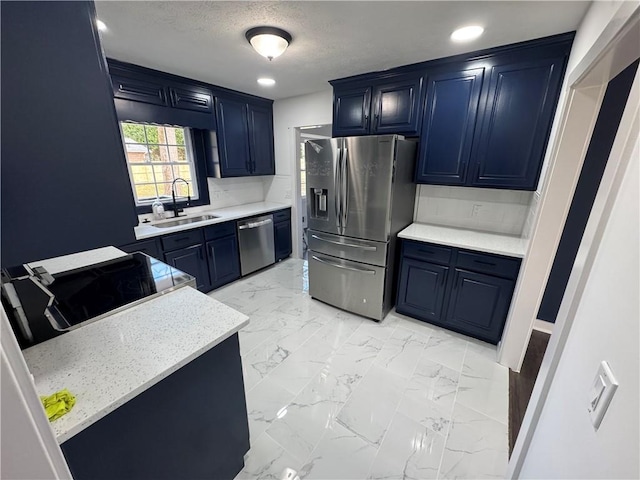 kitchen featuring blue cabinets, marble finish floor, stainless steel appliances, light countertops, and a sink