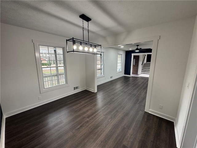 unfurnished dining area with visible vents, dark wood finished floors, stairway, and baseboards