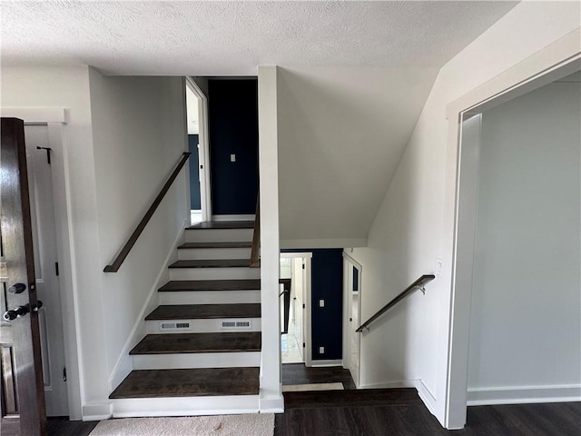 staircase featuring a textured ceiling, wood finished floors, and visible vents