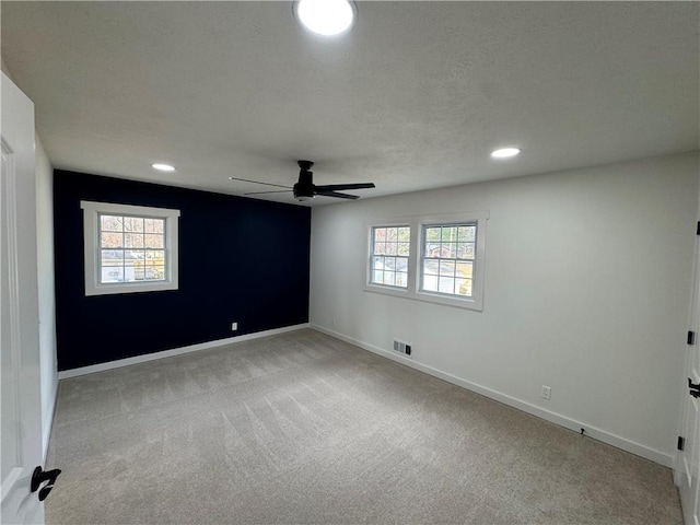 empty room with recessed lighting, light colored carpet, visible vents, a ceiling fan, and baseboards