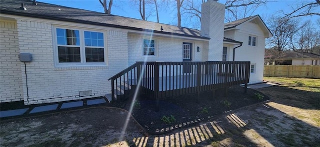 rear view of house featuring a deck, brick siding, fence, crawl space, and a chimney