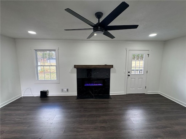 unfurnished living room with dark wood-style floors, a fireplace, visible vents, and plenty of natural light