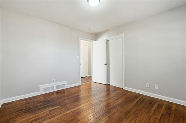 unfurnished bedroom featuring dark hardwood / wood-style flooring and a closet