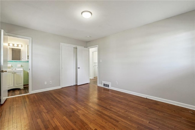 unfurnished bedroom featuring dark wood-type flooring, a closet, and connected bathroom