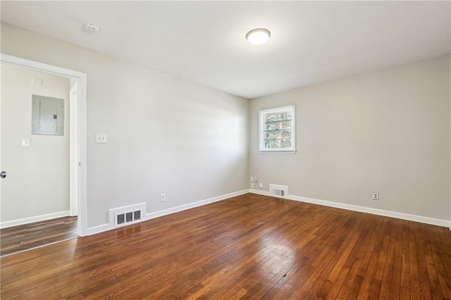 spare room with dark hardwood / wood-style flooring and electric panel