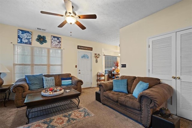 living room featuring ceiling fan, carpet, and a textured ceiling