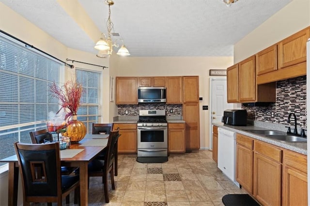 kitchen with tasteful backsplash, stainless steel appliances, sink, and hanging light fixtures