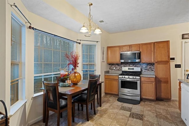 kitchen featuring stainless steel appliances, pendant lighting, backsplash, and a chandelier