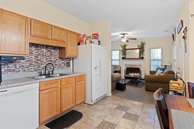 kitchen with light brown cabinetry, sink, decorative backsplash, ceiling fan, and white appliances