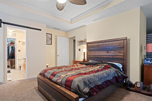 bedroom featuring ensuite bath, ornamental molding, a raised ceiling, light colored carpet, and a barn door