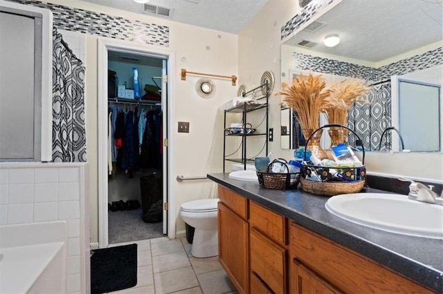 bathroom with vanity, a bathing tub, tile patterned flooring, and a textured ceiling