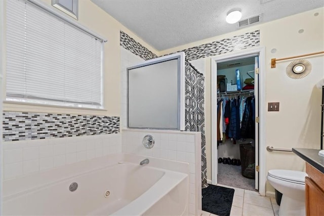 full bathroom with separate shower and tub, vanity, a textured ceiling, tile patterned floors, and toilet