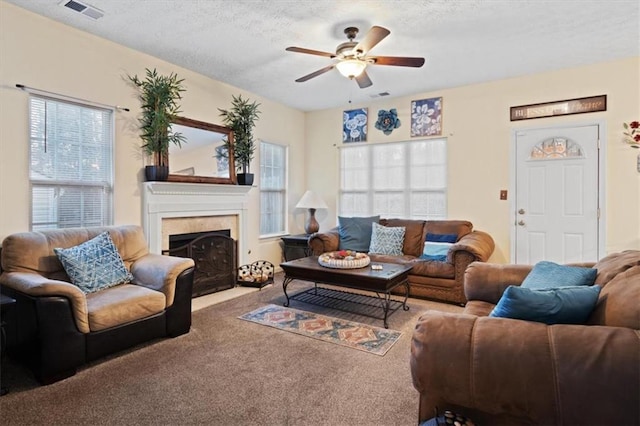 living room featuring ceiling fan, a high end fireplace, carpet, and a textured ceiling