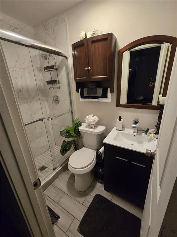 bathroom featuring visible vents, vanity, a shower stall, and toilet