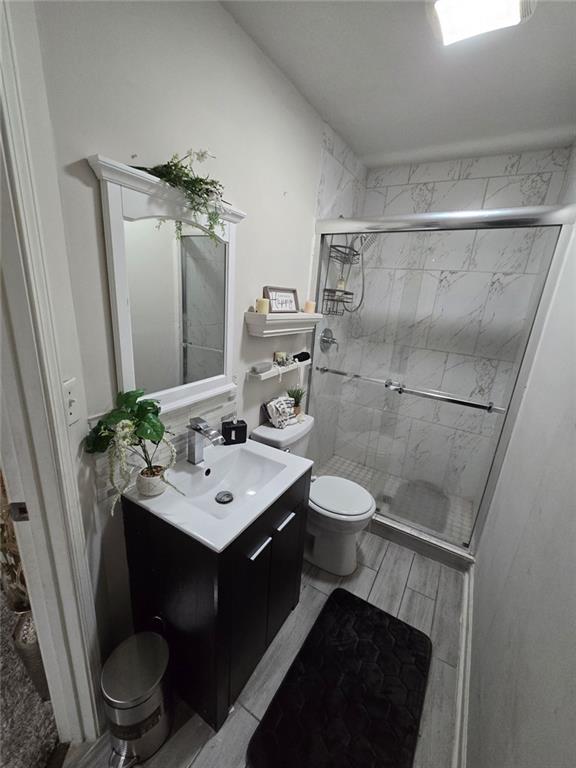 full bathroom with vanity, a shower stall, toilet, and wood tiled floor