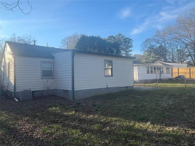 view of side of home featuring a yard, crawl space, central AC, and fence