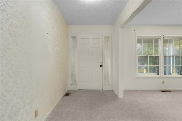 doorway with light colored carpet and a textured ceiling