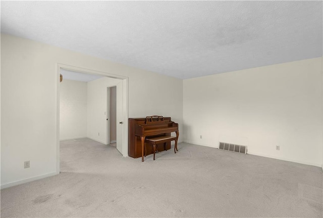 unfurnished room featuring a textured ceiling and light carpet