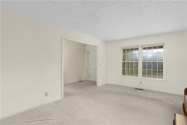 unfurnished room with light colored carpet and a textured ceiling