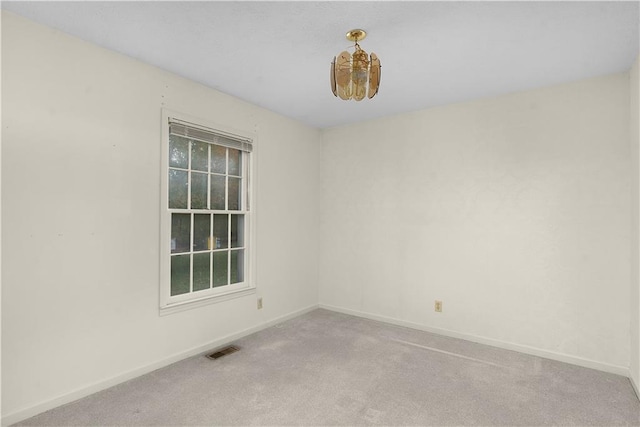 carpeted empty room featuring an inviting chandelier