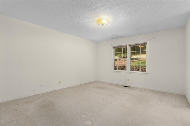 unfurnished room with light colored carpet and a textured ceiling