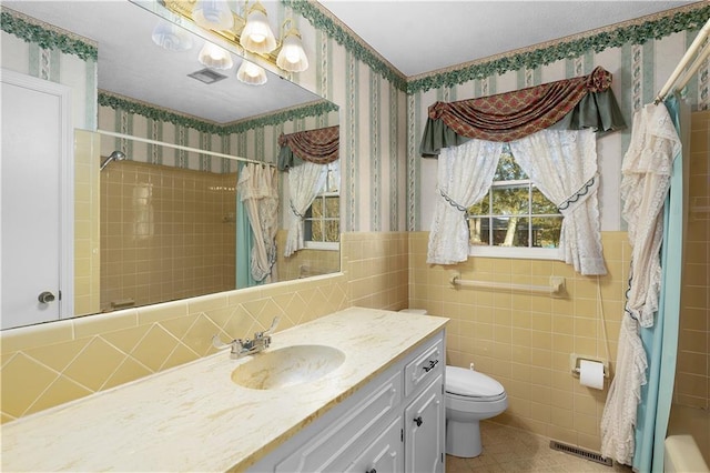 full bathroom featuring vanity, shower / bath combination with curtain, toilet, and tile walls