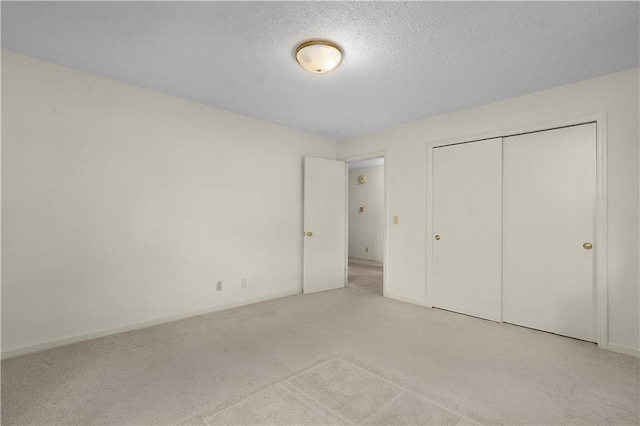 unfurnished bedroom featuring a closet, light colored carpet, and a textured ceiling