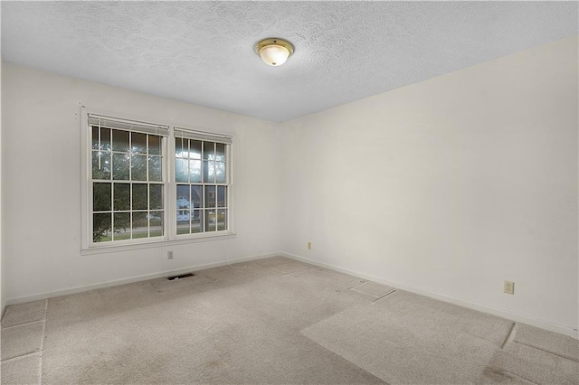 carpeted empty room featuring a textured ceiling