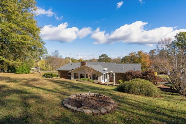 rear view of house with a lawn and a fire pit