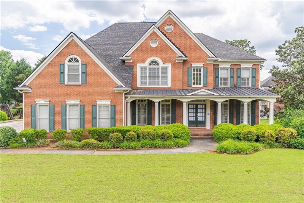 1900 Briergate Dr, Duluth, GA 30097 - view of front of house featuring brick siding, a front yard, covered porch, and a standing seam roof