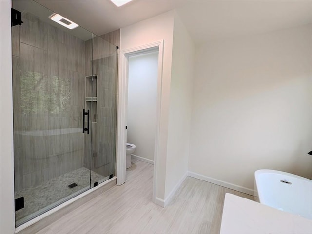 bathroom featuring toilet, wood finished floors, baseboards, and a shower stall