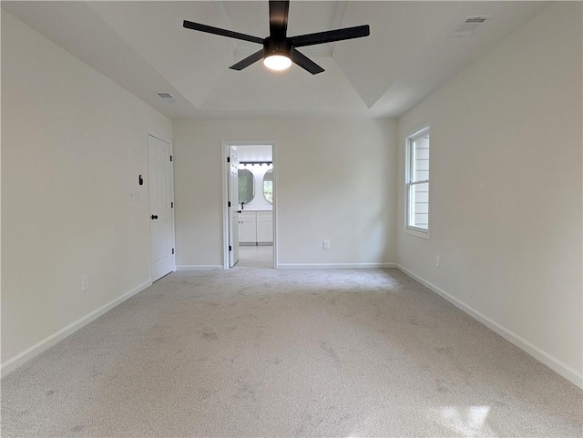 empty room with a ceiling fan, a raised ceiling, baseboards, and visible vents