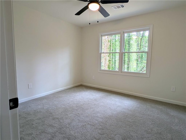 spare room with baseboards, carpet floors, visible vents, and a ceiling fan