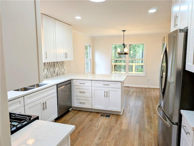 kitchen with light wood-style flooring, white cabinets, a peninsula, and stainless steel appliances