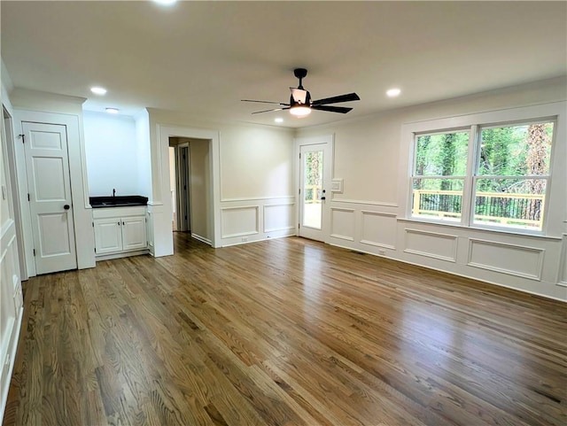 unfurnished living room featuring a decorative wall, wood finished floors, ceiling fan, and recessed lighting