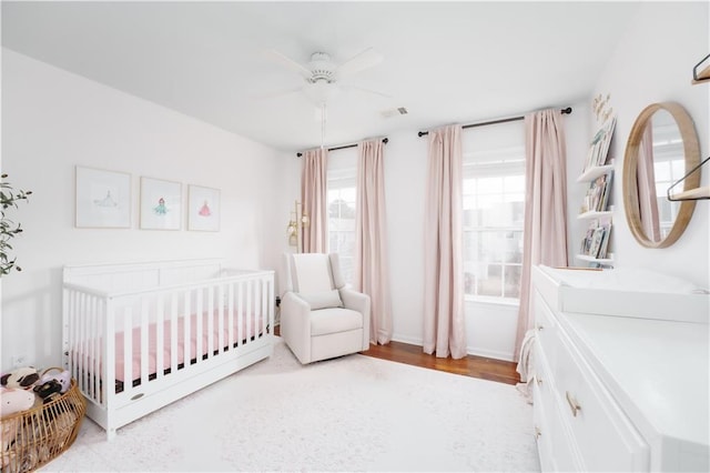 bedroom with ceiling fan and a crib